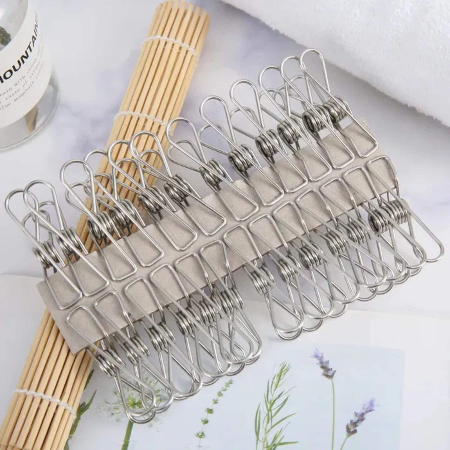 Metal clothespins on a white surface with wooden sticks and lavender flowers.